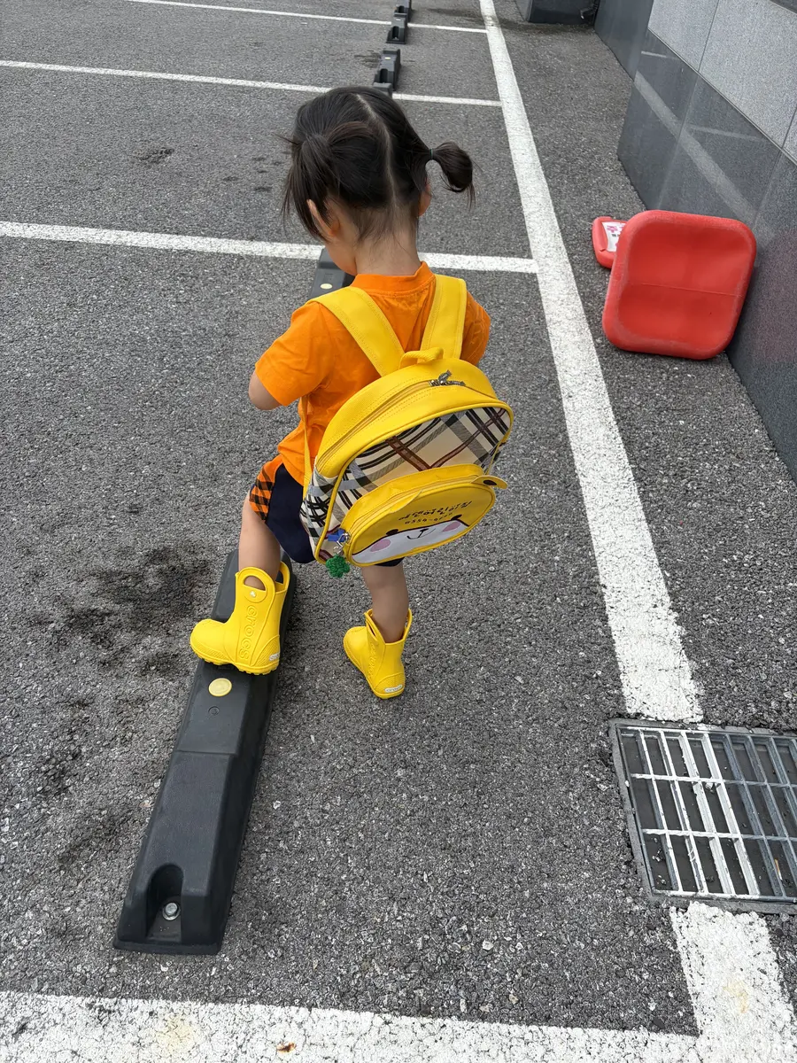 노란색 크록스 키즈 장화를 신고 걷는 아이